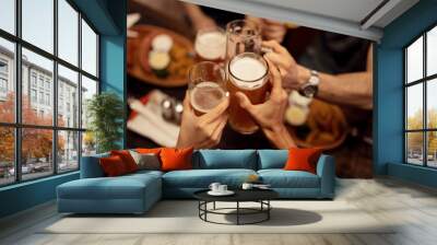 Close up of friends toasting with beer and having fun in a pub. Wall mural