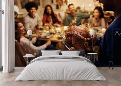 Close up of man serving roasted turkey during Thanksgiving dinner party with friend. Wall mural