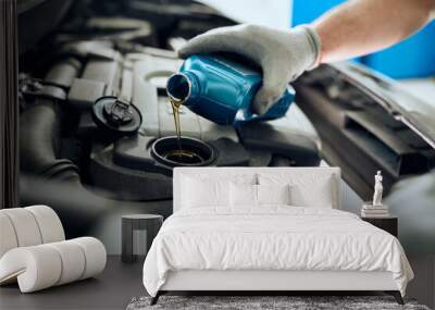 Close- up of mechanic pours motor oil while doing car engine maintenance at auto repair shop. Wall mural