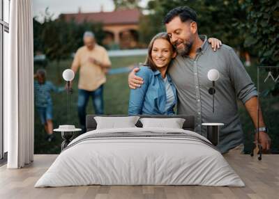 Embraced teenager girl and her father walk through backyard. Wall mural