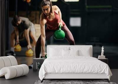 Female athlete having strength training with kettlebells in health club. Wall mural