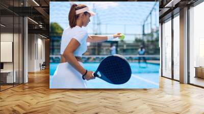 Female paddle tennis player serving the ball during  match. Wall mural