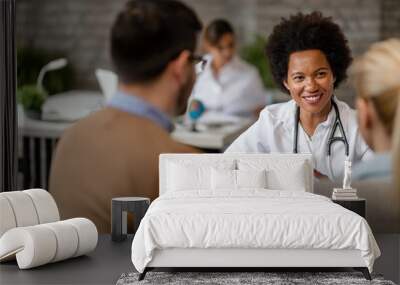 Happy African American doctor having consultations with a couple. Wall mural