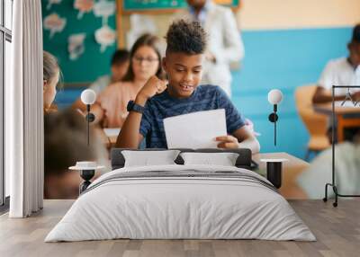 Happy African American schoolboy celebrates excellent grade on an elementary school test. Wall mural