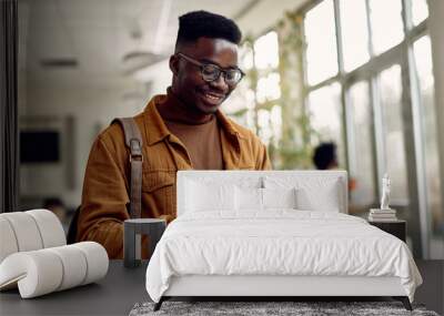 Happy African American student uses digital tablet at university hallway. Wall mural