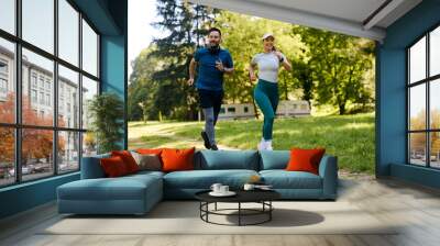 Happy athletic couple jogging during sports training in nature. Wall mural