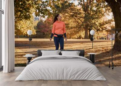 Happy athletic woman taking a walk through autumn park. Wall mural