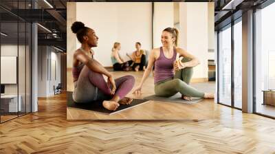 Happy athletic women talk while relaxing after exercising at health club. Wall mural