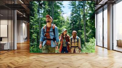 Happy backpacker and his friends hiking in forest. Wall mural