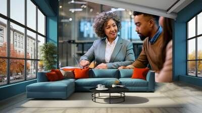 Happy bank manager using laptop while consulting young couple in office. Wall mural