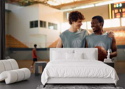 Happy basketball players talking during sports training at indoor court. Wall mural