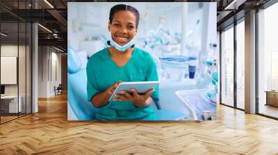 Happy black dentist working on touchpad in her office and looking at camera. Wall mural