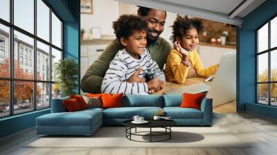 Happy black father and children having video call over laptop at home. Wall mural