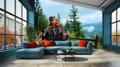 Happy black female hiker enjoys in walk in mountains. Wall mural