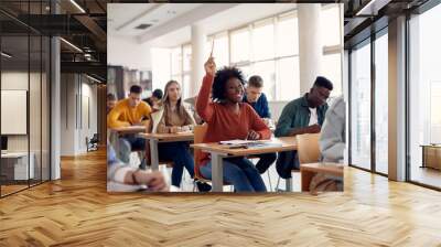 Happy black student raising arm to answer question while attending class with her university colleagues. Wall mural