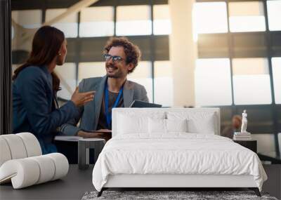 Happy businessman talking to female colleague while using laptop in convention center. Wall mural