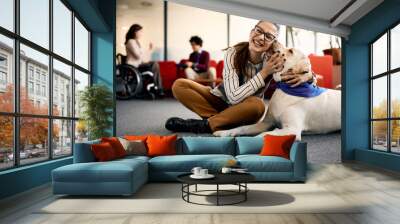 Happy businesswoman embraces her Labrador therapy dog and having fun in office. Wall mural