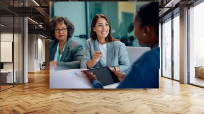 Happy businesswoman talking to her colleagues during meeting in office. Wall mural