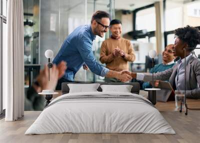 Happy CEO handshaking with black female colleague during business meeting in office. Wall mural