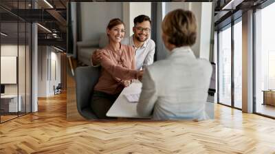 Happy couple greeting their real estate agent in the office. Wall mural