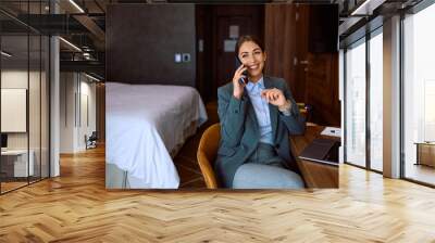 Happy entrepreneur talking on cell phone from hotel room during her business trip. Wall mural