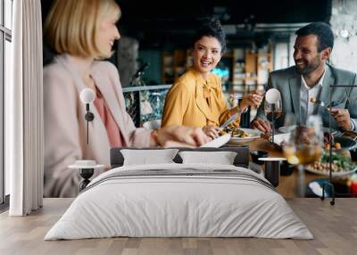 Happy entrepreneur talks to her coworkers during business lunch in restaurant. Wall mural