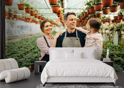 Happy family communicating while working in their greenhouse. Wall mural