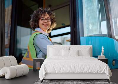 Happy female bus driver entering in vehicle and looking at camera. Wall mural