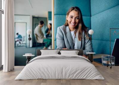 Happy female entrepreneur working in office and looking at camera. Wall mural