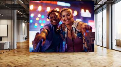 Happy female friends having fun on summer music festival at night and looking at camera. Wall mural