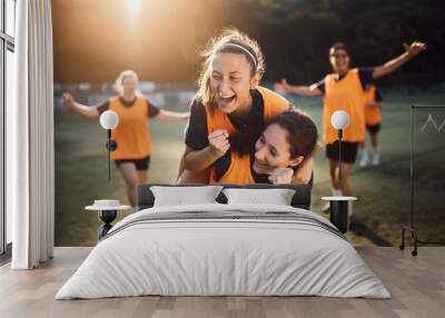 Happy female players celebrating a goal during soccer match at stadium. Wall mural