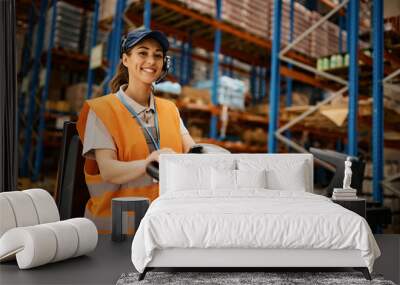 Happy female worker driving pallet jack while working at distribution warehouse. Wall mural