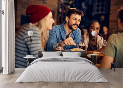 Happy man enjoys while communicating with his friends in pub. Wall mural