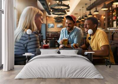 Happy man having fun while talking to his friends and drinking beer in pub. Wall mural