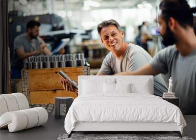 Happy manual workers talking while working together at steel factory. Wall mural