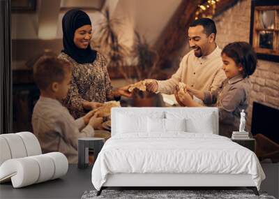 Happy Middle Eastern family shares pita bread at dining table on Ramadan. Wall mural