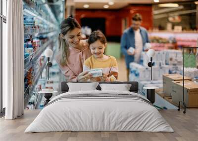 Happy mother and daughter buying diary products in supermarket. Wall mural