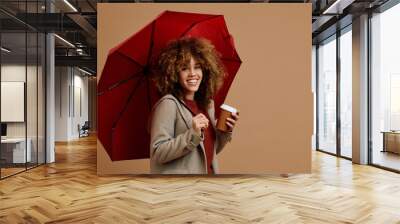 Happy multiracial woman with takeaway coffee and red umbrella looking at camera. Wall mural