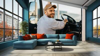 Happy professional driver entering in truck cabin and looking at camera. Wall mural