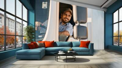 Happy professional truck driver driving his truck and looking at camera. Wall mural