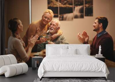 Happy senior couple celebrating marriage anniversary during family meal at home. Wall mural