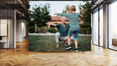 Happy senior woman greeting her son with arms outstretched in backyard. Wall mural