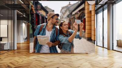 Happy tourist couple taking selfie while exploring  city. Wall mural