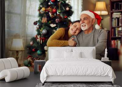 Happy woman embraces her senior father on Christmas day at home. Wall mural