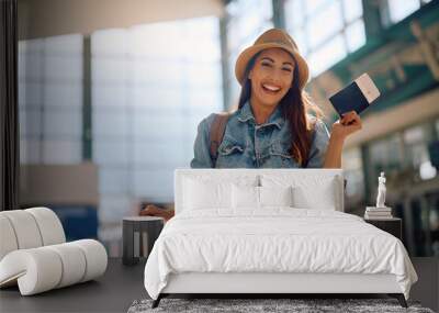 Happy woman holding her passport and plane ticket at departure area and looking at camera. Wall mural