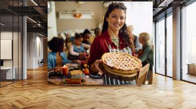 Happy woman with Thanksgiving pie during family meal in dining room looking at camera. Wall mural