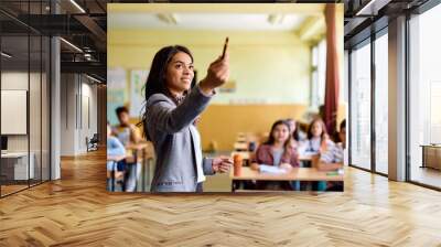 Hispanic elementary school teacher explains new lecture to her students during class. Wall mural