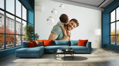 Little boy kisses his father who is piggybacking him while spending time together at home. Wall mural