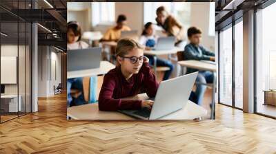 Little girl e-learns on laptop in computer science classroom at elementary school. Wall mural