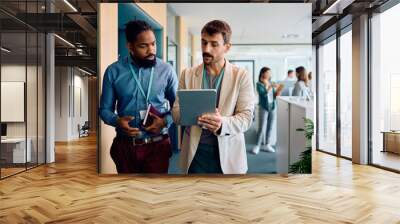 Male entrepreneurs cooperating while working on digital tablet in office. Wall mural